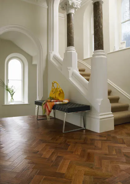 Auburn oak parquet laid in a herringbone pattern across a pillared Georgian hallway.