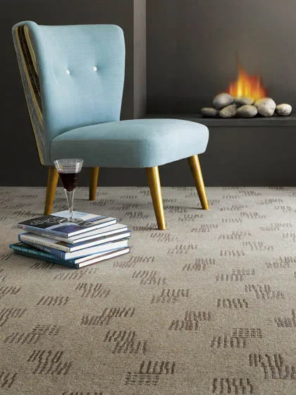Oatmeal carpet with a woven dash pattern, in a room with a pale blue cocktail chair beside a fireplace.