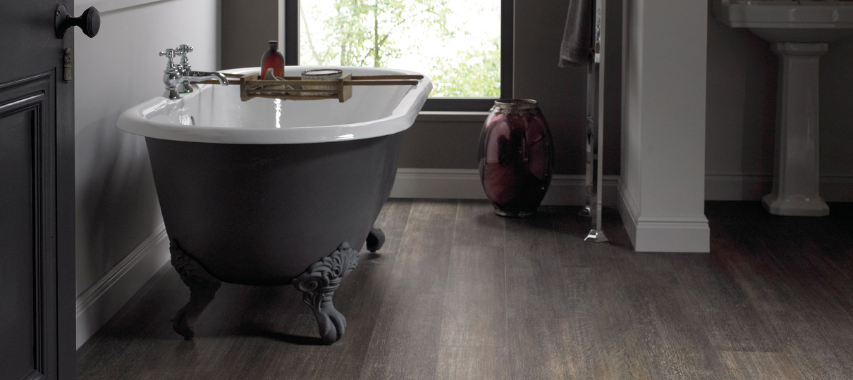Dark smoked-oak plank flooring in a bathroom with a grey cast-iron roll-top bath.
